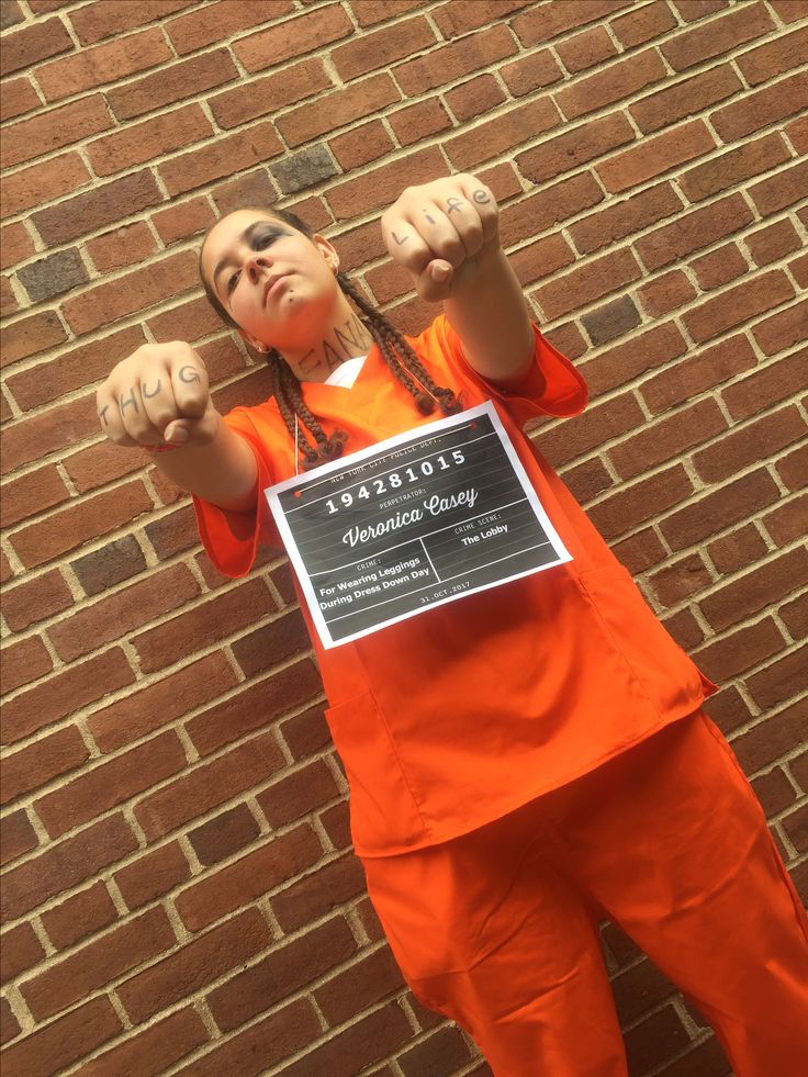 a woman in an orange prison uniform holding up two fists