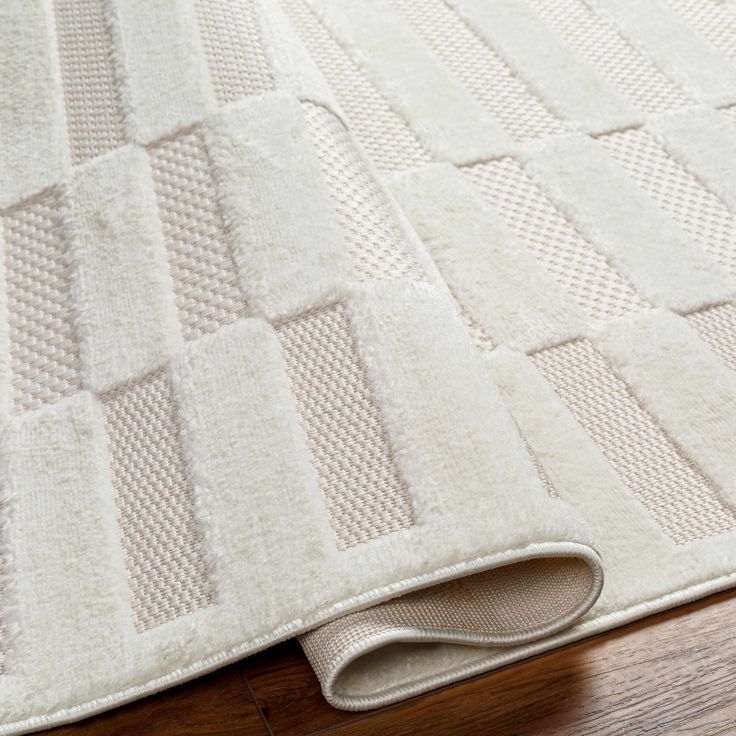 a close up of a white rug on a wooden floor with a wood floor mat