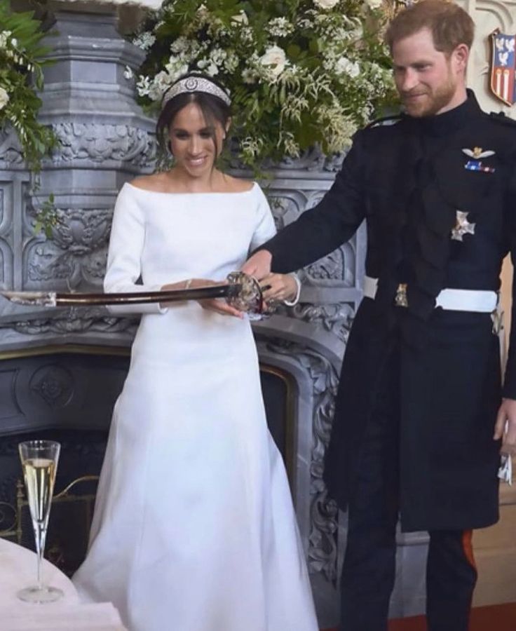 prince harry and his bride are smiling at each other as they stand in front of a fireplace