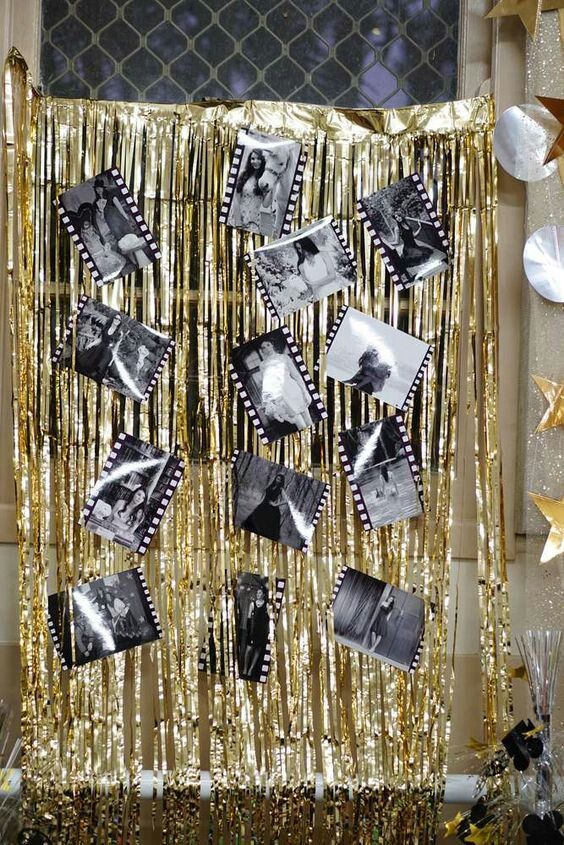 a gold curtain with pictures hanging from it and streamers around the edges that are filled with confetti