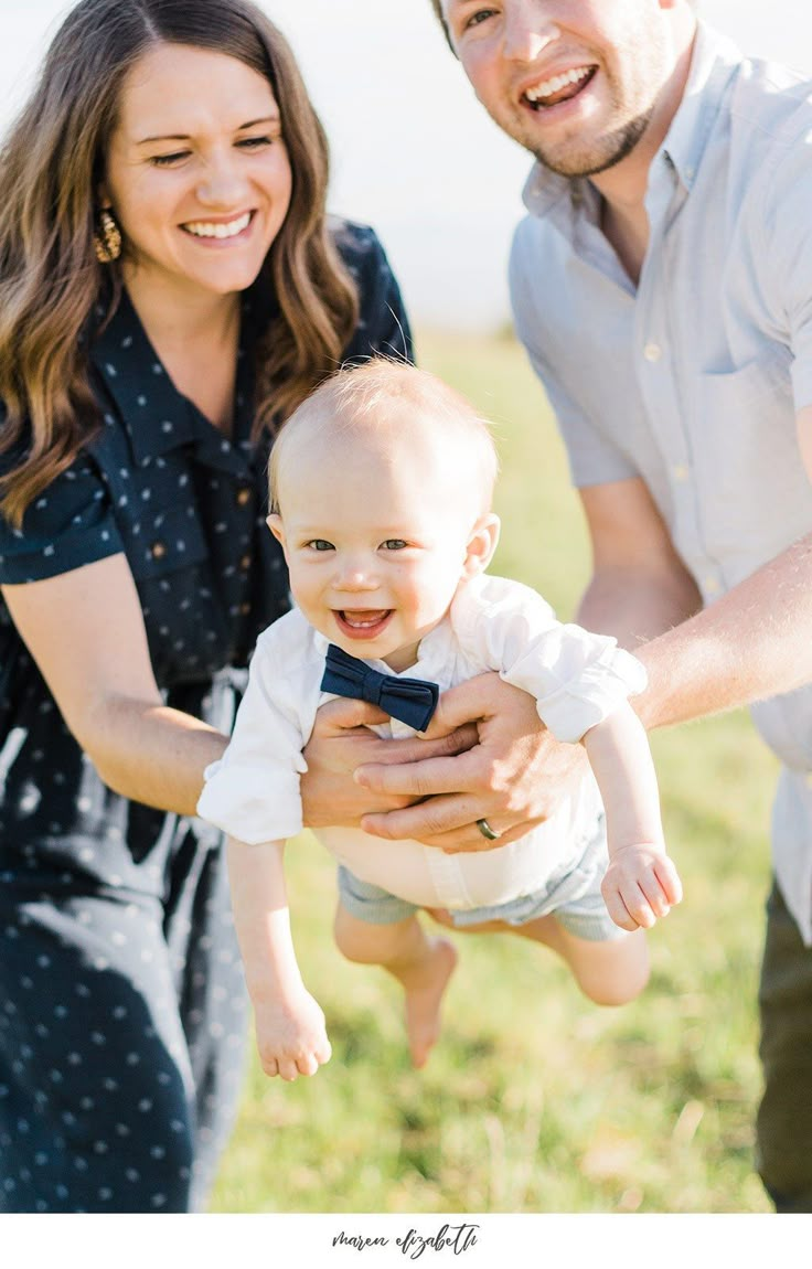 a man and woman holding a baby in their arms while they smile at the camera