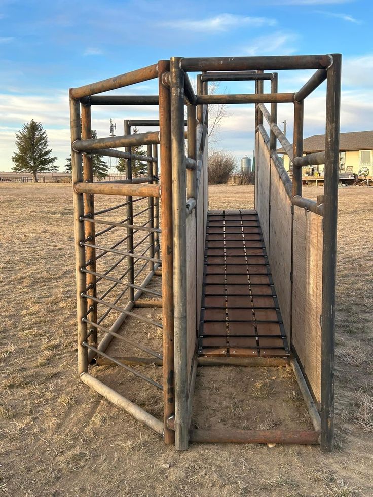 a wooden structure in the middle of a field with metal bars on it's sides