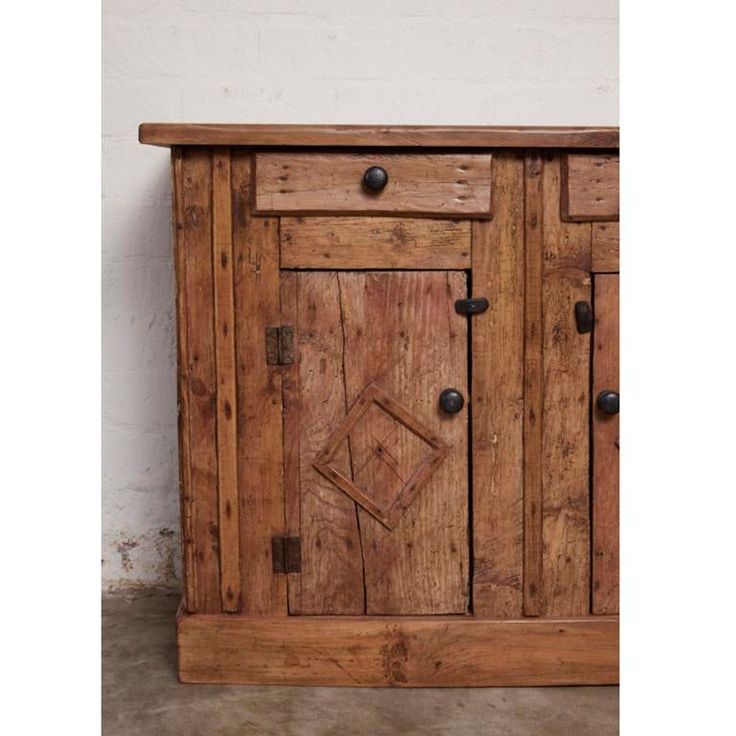 an old wooden cabinet with knobs on the doors and drawers is displayed against a white wall