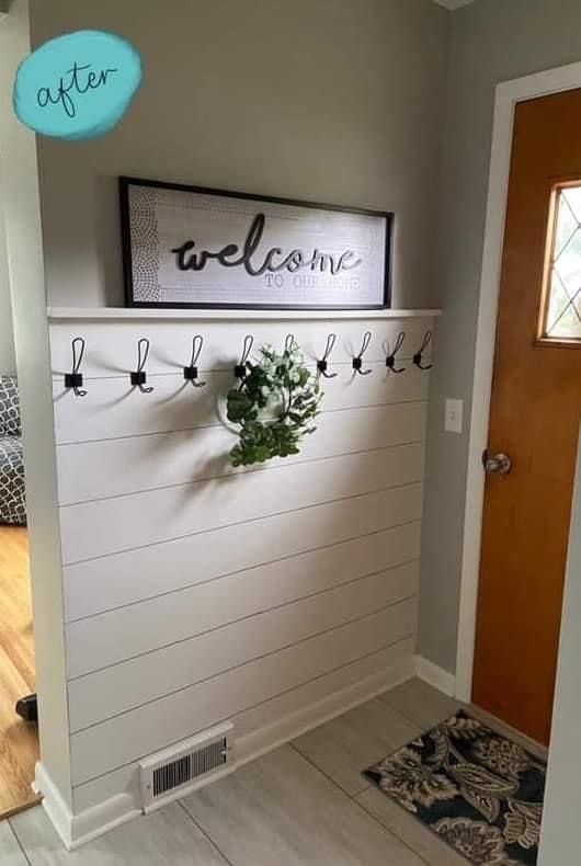 there is a welcome sign on the wall in this entry way with a potted plant