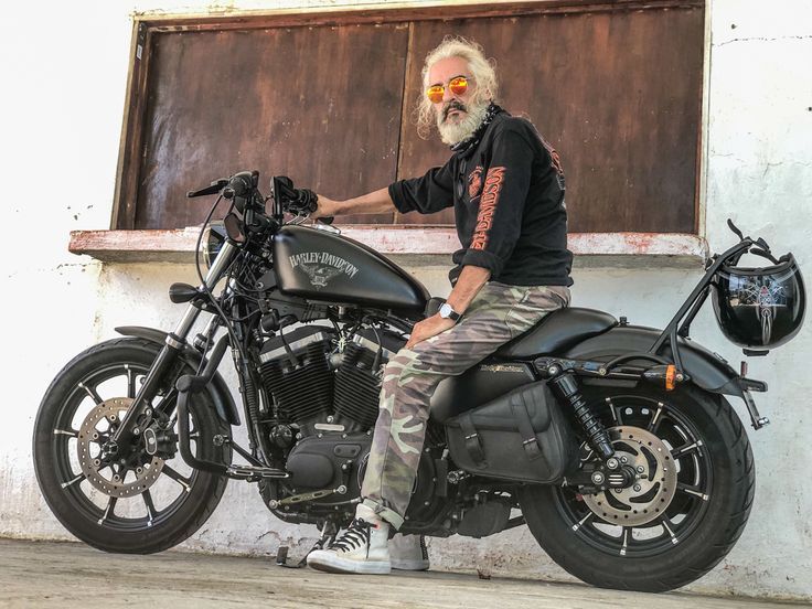 a man sitting on top of a black motorcycle next to a building with a window