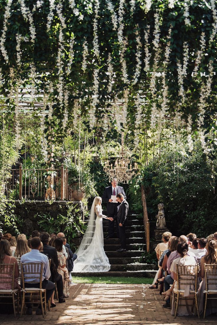 a bride and groom standing at the end of a set of steps in front of an outdoor ceremony