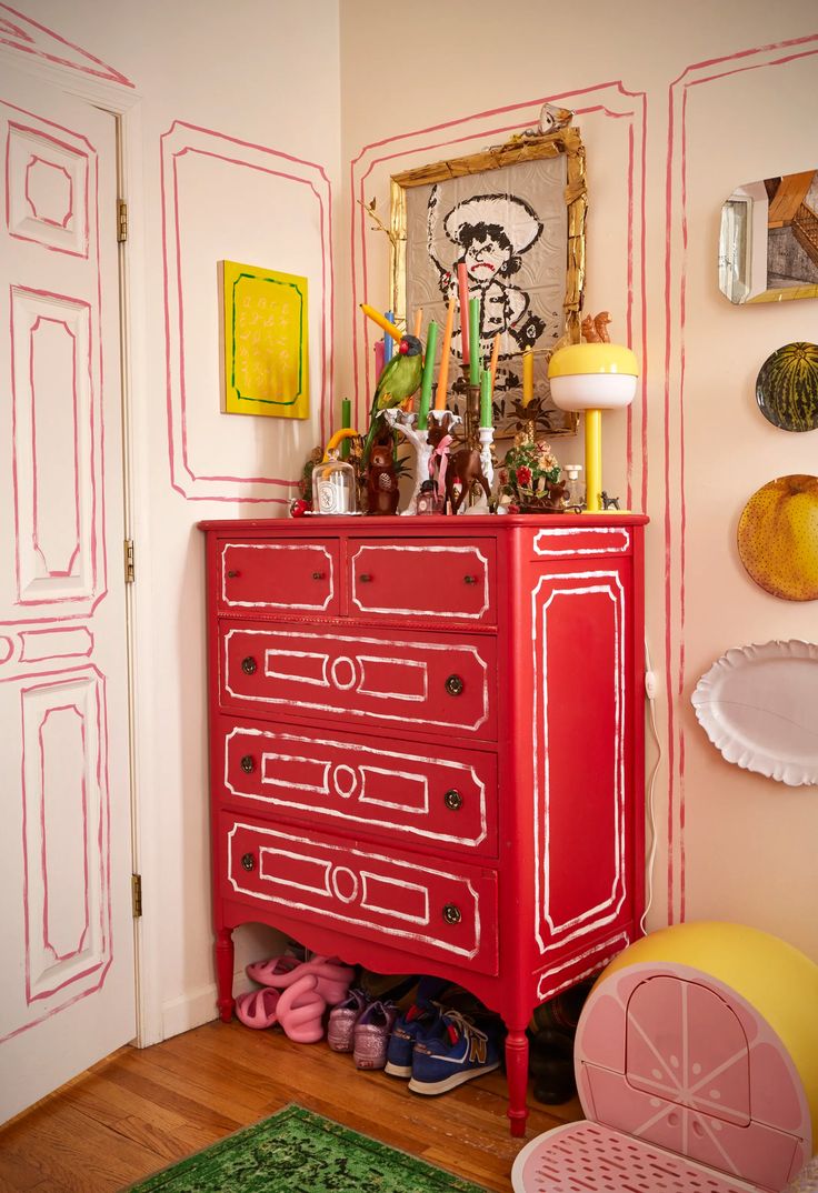 a red dresser in a room with pictures on the wall