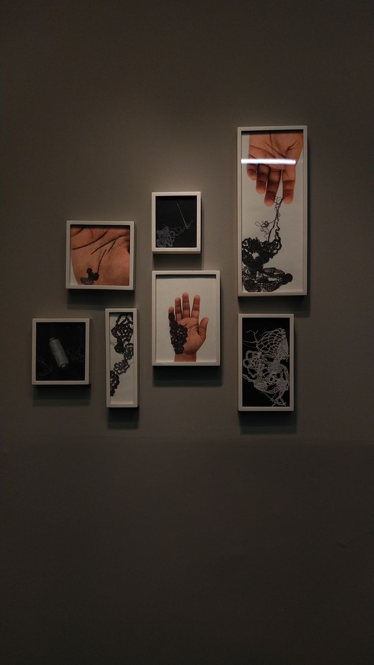 a wall with several pictures hanging on it's side and one person holding their hand up