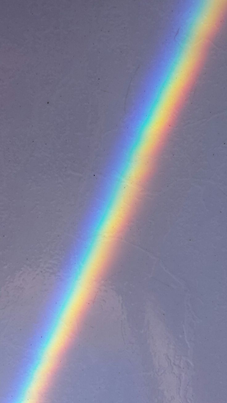 a rainbow appears in the sky above a snowboarder