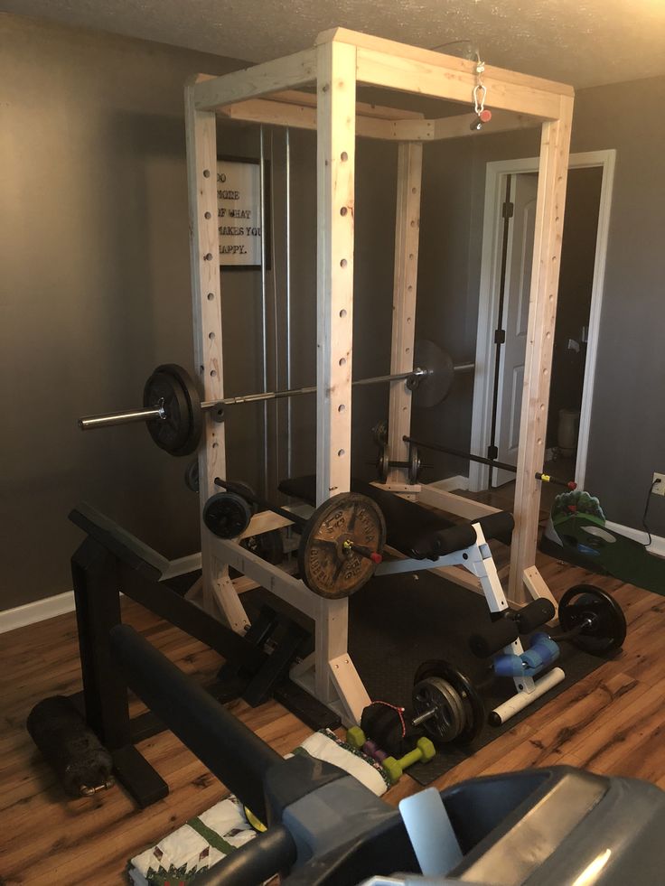 a home gym with two squat machines and one bench on the floor in front of an open door