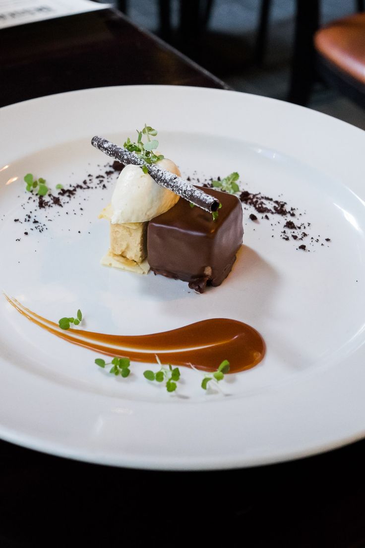 a white plate topped with a piece of cake covered in chocolate