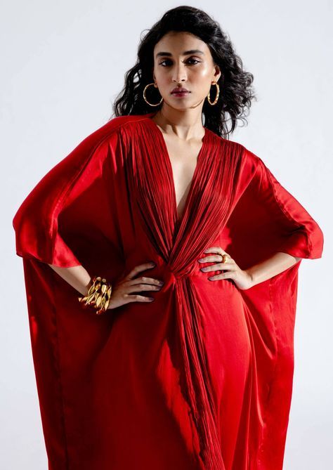 Introducing our regal red kaftan in luxurious modal satin, a versatile and striking piece that effortlessly adapts to any occasion. With a beautifully ruched v-neckline and a flowing kaftan silhouette, this garment in bold red is the perfect choice to dress up or down, making it suitable for a wide range of settings. Formal Festive V-neck Kaftan, Elegant Draped Kaftan With Draped Sleeves, Festive Silk V-neck Dress, Elegant Draped Kaftan For Festive Season, Elegant Draped Kaftan For Festive Occasions, Elegant Draped Festive Kaftan, Festive V-neck Kaftan, Red Silk Kaftan For Wedding, Draped Kaftan For Wedding