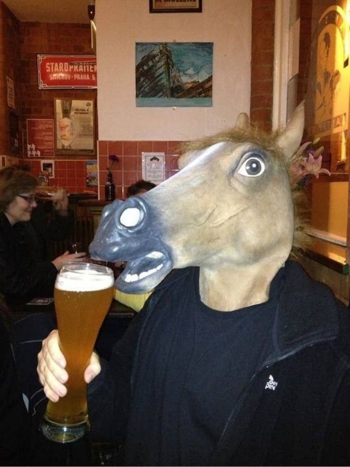 a man in a horse mask holding a beer