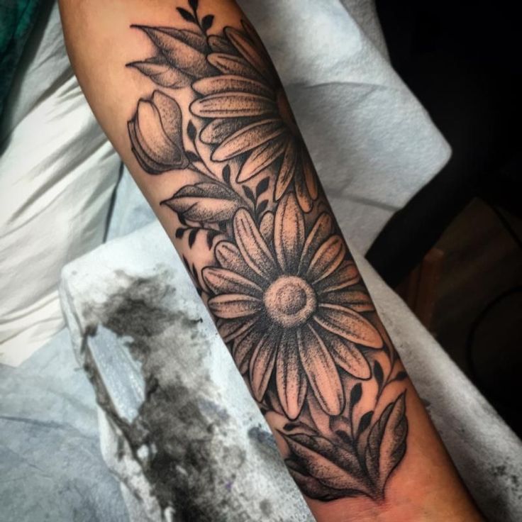 a woman's arm with a sunflower tattoo on it