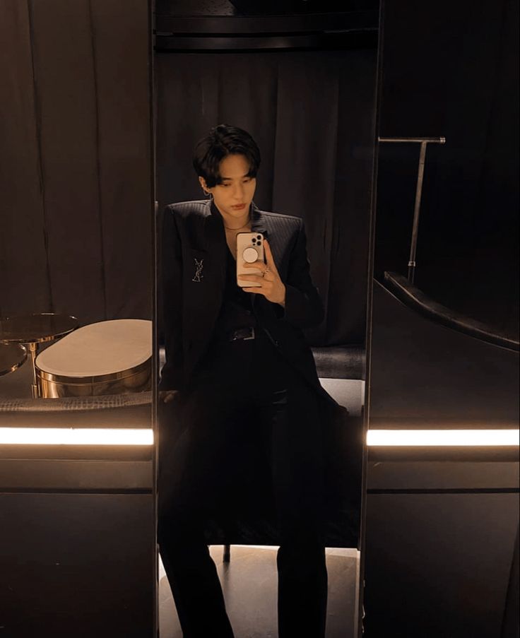 a young man taking a selfie in front of a mirror with his cell phone