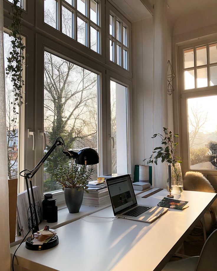 a laptop computer sitting on top of a white desk next to a window with lots of windows