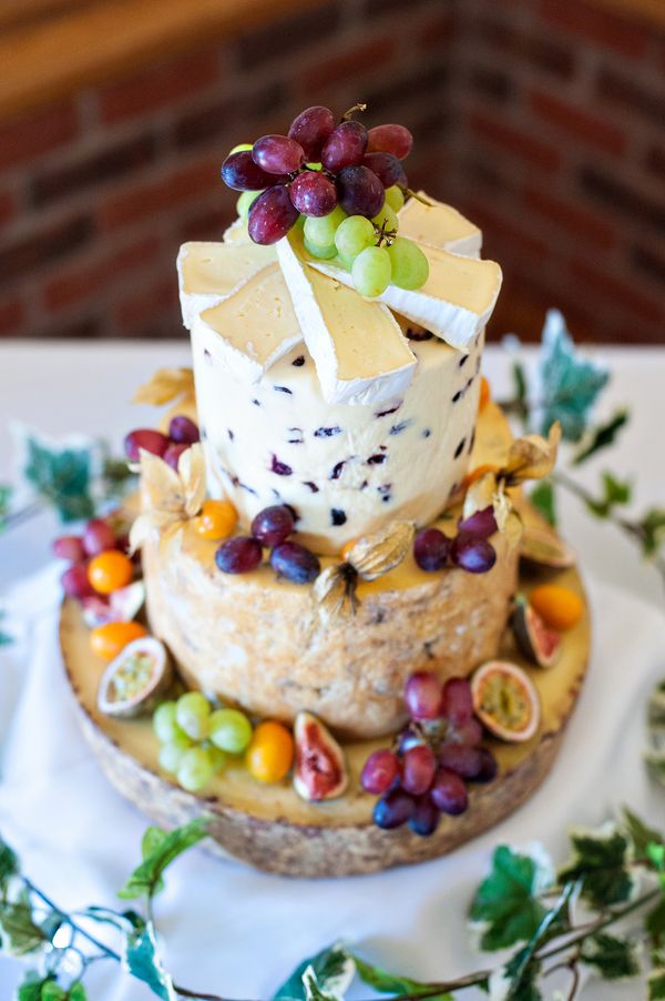 a three tiered cake decorated with grapes and cheese