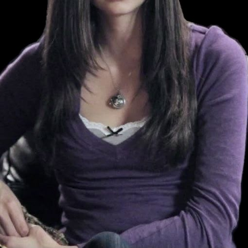 a woman with long hair sitting down and looking at the camera while wearing a purple shirt