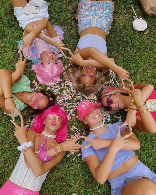 a group of young women laying on top of a lush green field next to each other