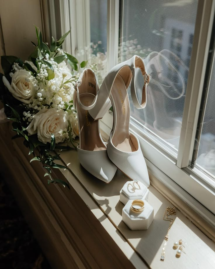 a pair of white shoes sitting on top of a window sill next to flowers