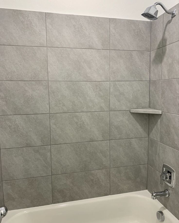 a white bath tub sitting next to a tiled wall