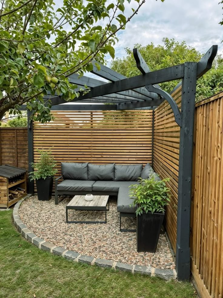 an outdoor seating area in the middle of a yard with wooden fence and plants on it