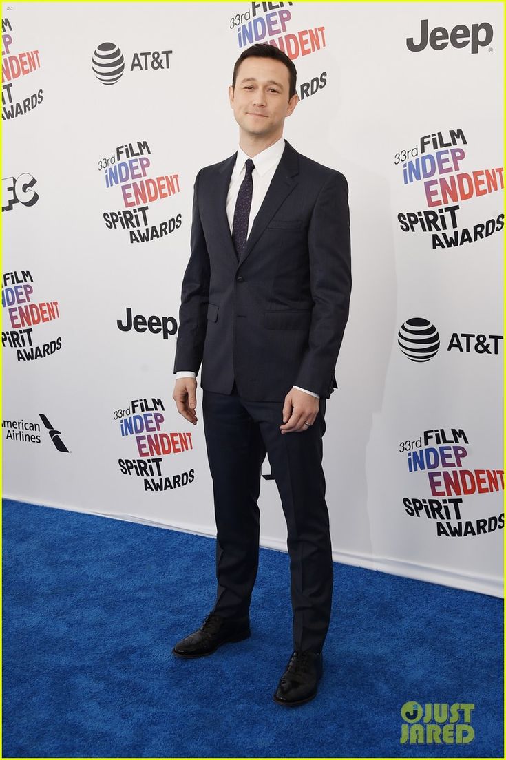 a man in a suit and tie on the blue carpet at an awards event with his hands in his pockets