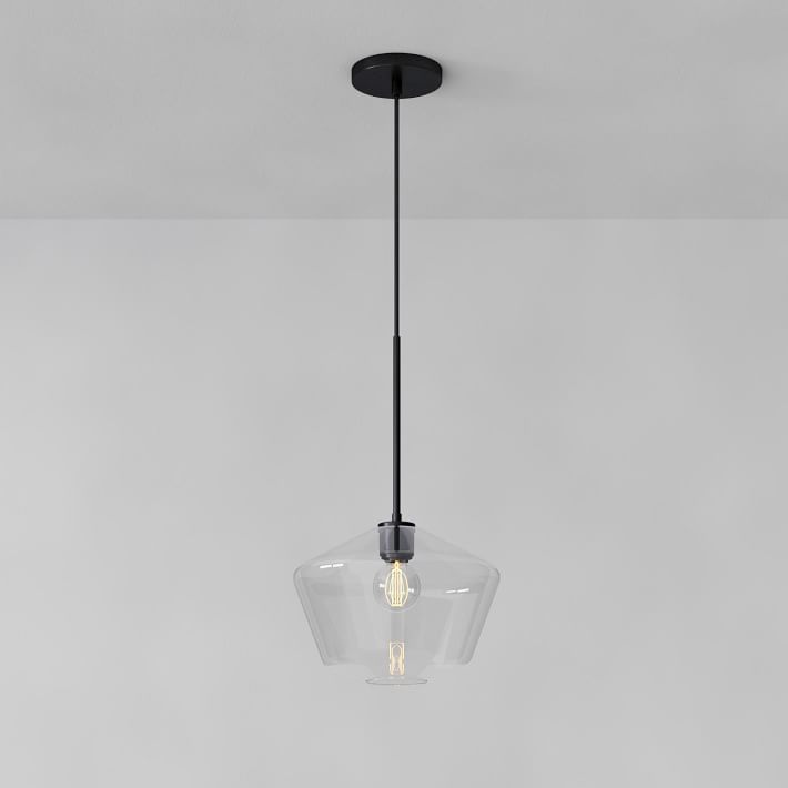 a clear glass light fixture hanging from a ceiling in a room with gray walls and flooring