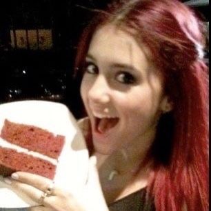 a woman with red hair holding up a piece of cake