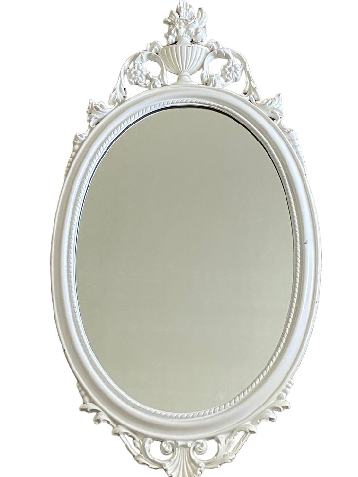 an ornate white framed mirror on a wall