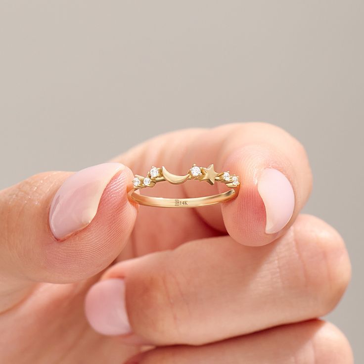 a woman's hand holding a gold ring with three small diamonds on the side