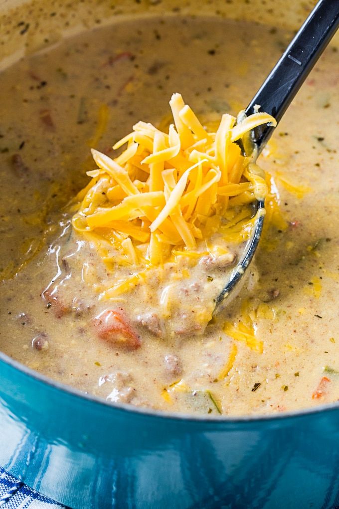 a blue pot filled with soup and cheese