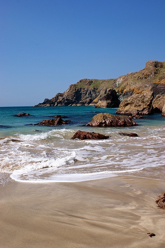 the beach has waves coming in and out of the water on it's shore