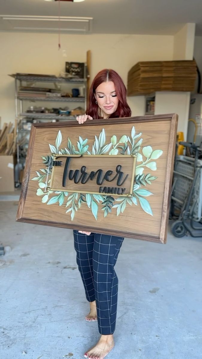 a woman holding up a wooden sign that says turmer family