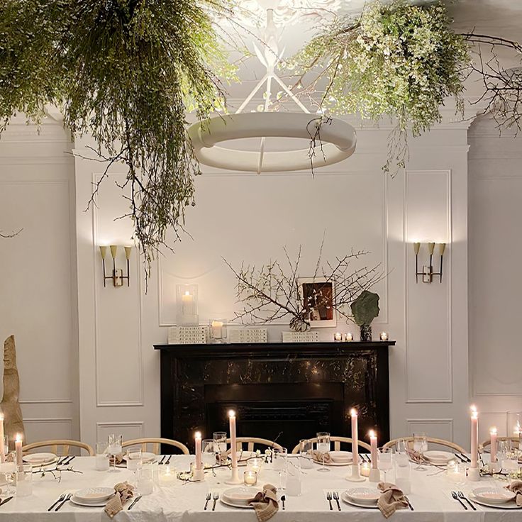 a dining room table is set with place settings and candles in front of the fireplace