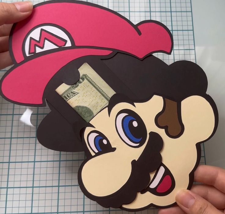 a paper cut out of mario with money sticking out of it