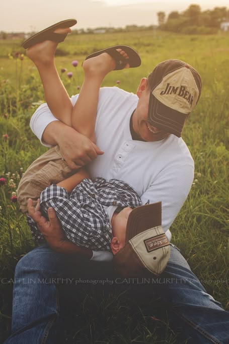 a man holding a baby while sitting in the grass