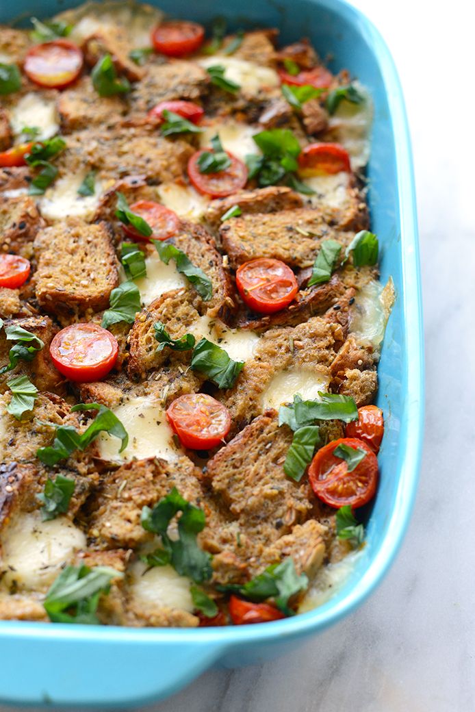 a casserole dish filled with meat, cheese and tomatoes on a marble surface