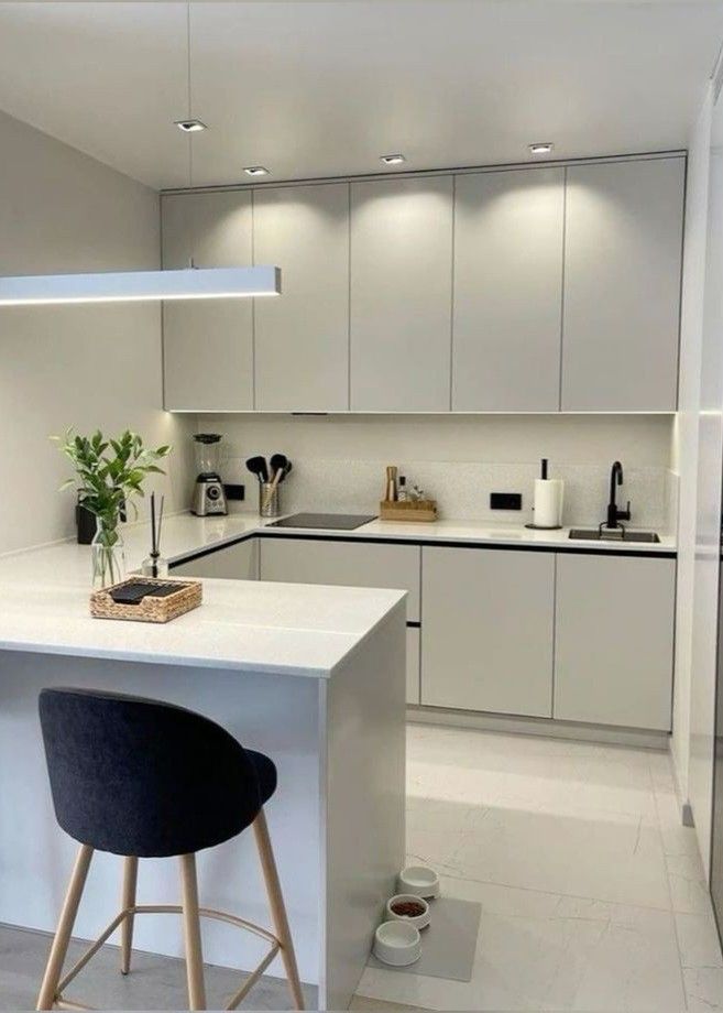 a white kitchen with two stools next to an island