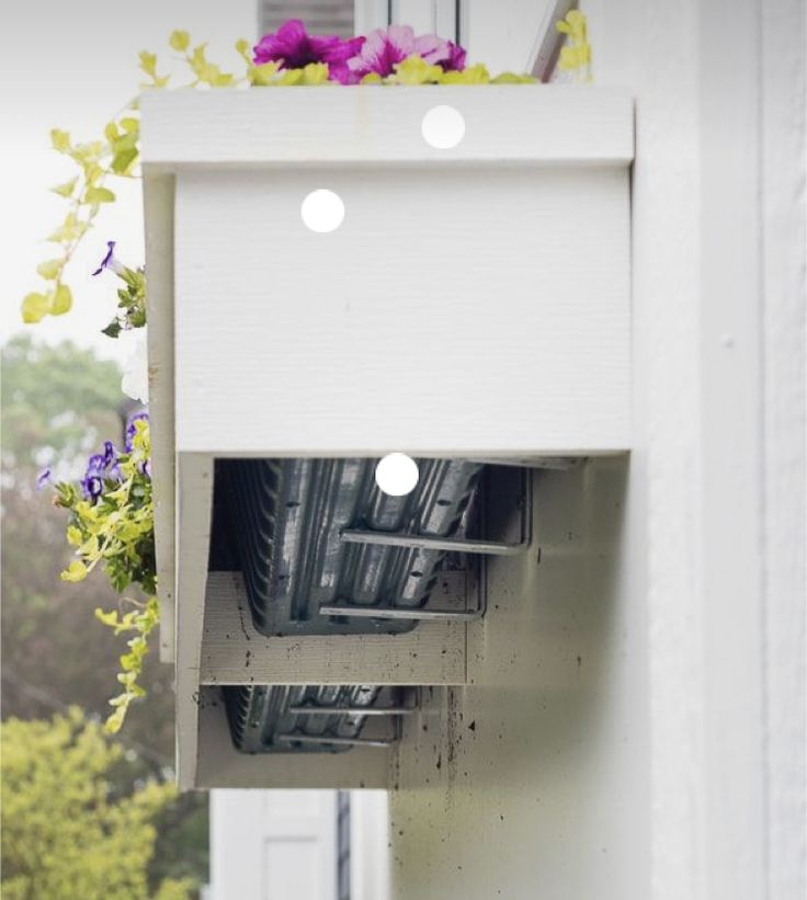 an open window on the side of a building with flowers hanging from it's windowsill