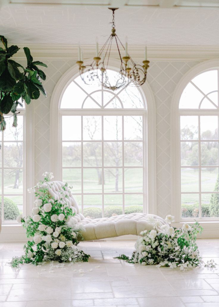 a room with large windows and white flowers on the floor