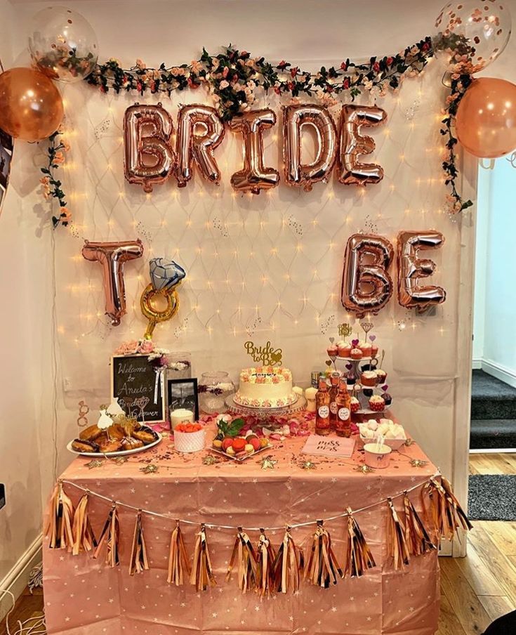 a table topped with lots of food and balloons in front of a sign that says bride to be