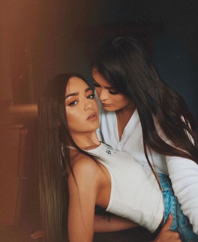 two beautiful women hugging each other in front of a mirror with their arms around one another