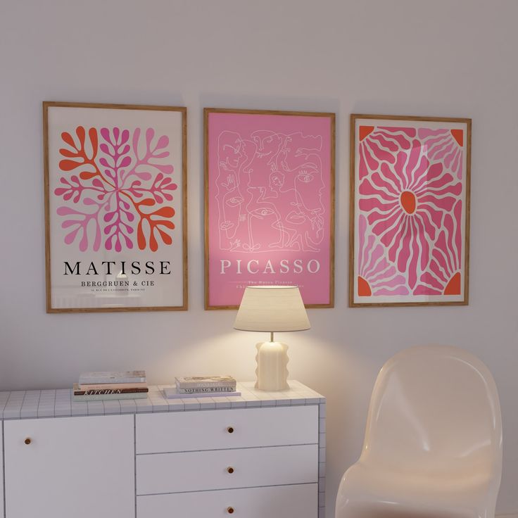 a white dresser topped with a lamp next to two pictures on the wall above it