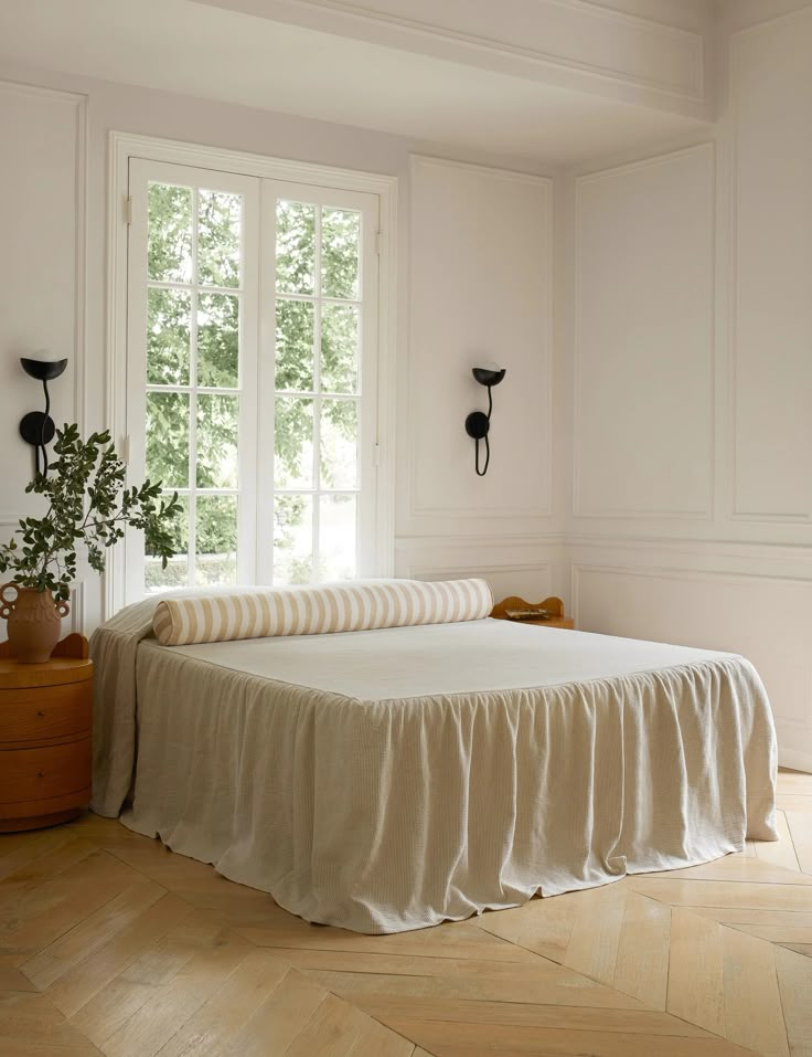 a bed sitting in the middle of a bedroom next to a window and wooden floor