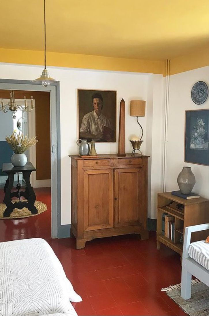 a bedroom with red tile flooring and yellow painted walls, along with a painting on the wall