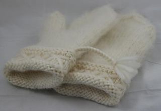 a white knitted mitten laying on top of a bed