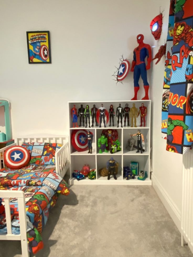 a bedroom with a bed, toy shelves and spiderman wall decals on the walls