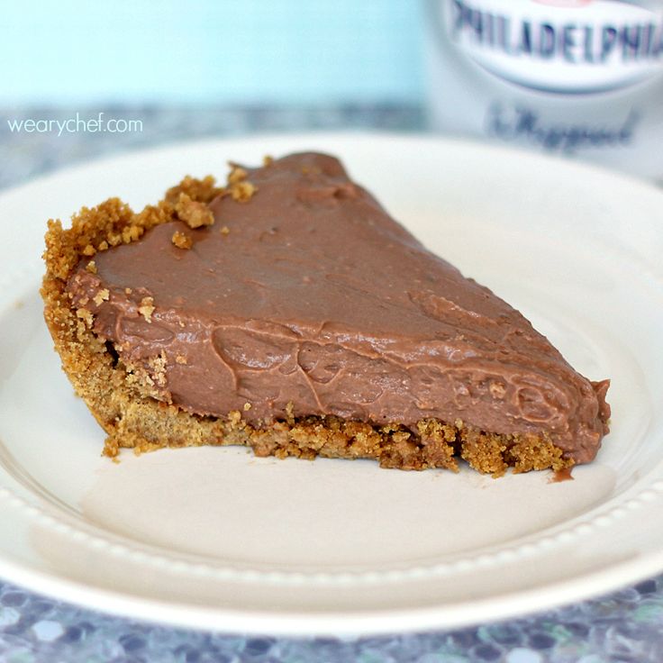 a piece of chocolate pie on a white plate with a blue table cloth behind it