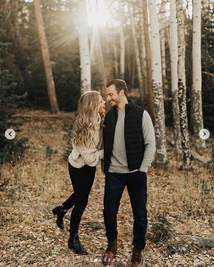 a man and woman are standing in the woods